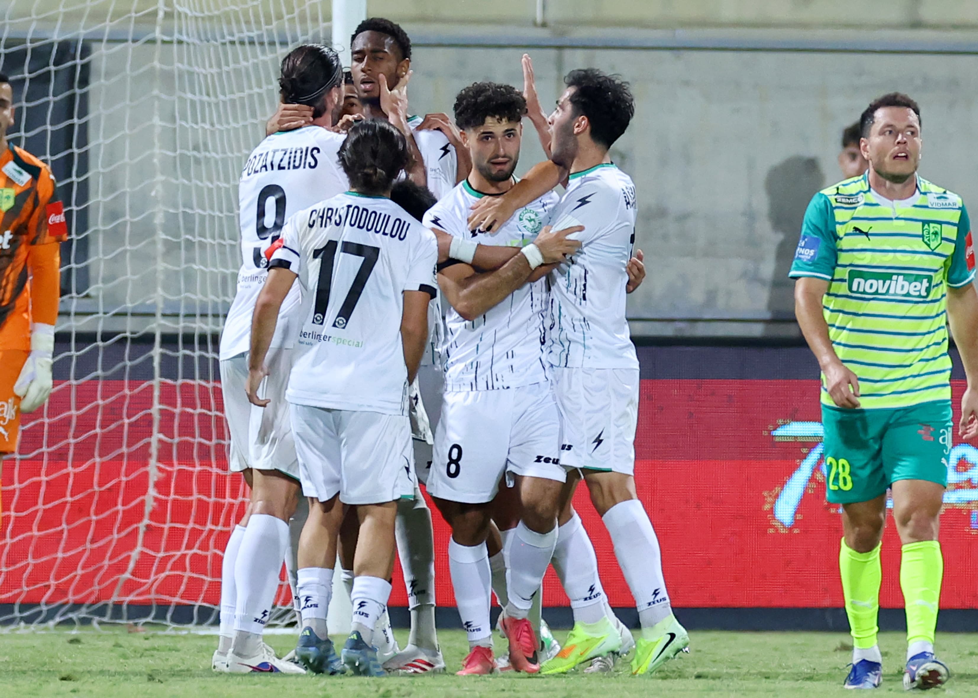 Akritas players gather around Charis Pozatzidis after his goal